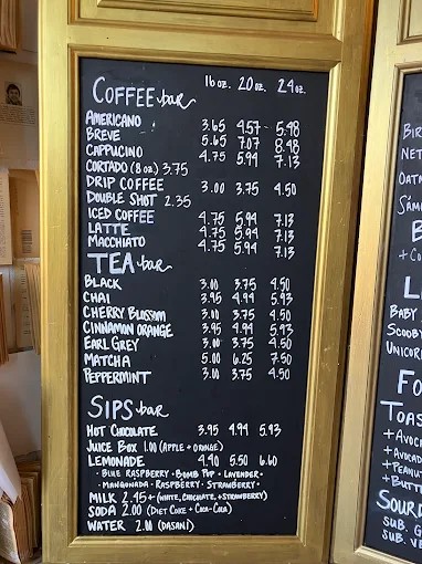 The cafe's chalkboard drink menu in a gold frame